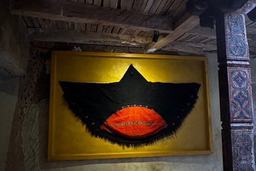 A framed artwork with a black and orange design, possibly a mask, on a yellow background. 2