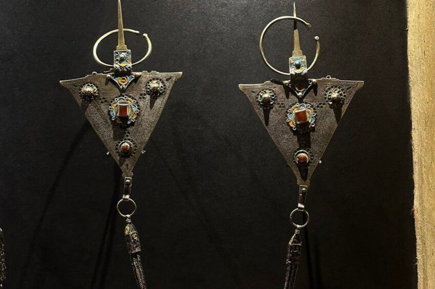 Two triangular metal objects with rings and chains, possibly jewelry, against a dark background. 4