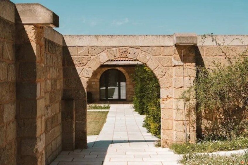 A stone archway leading to a building with a tiled pathway. 5