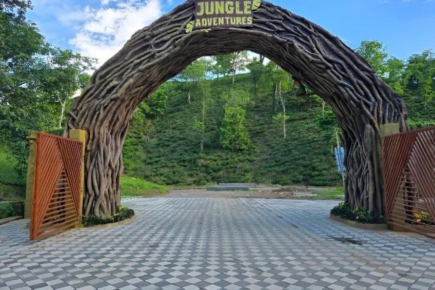 A large wooden archway with the words 'Jungle Adventures' on it, leading into a forested area. 1