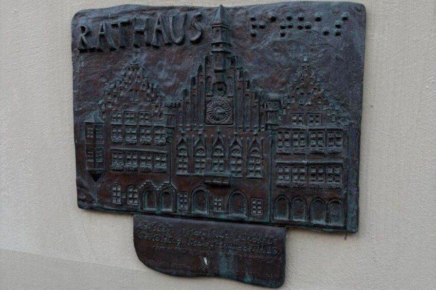 A metal plaque with a building illustration and the text 'RATHAUS'. 5
