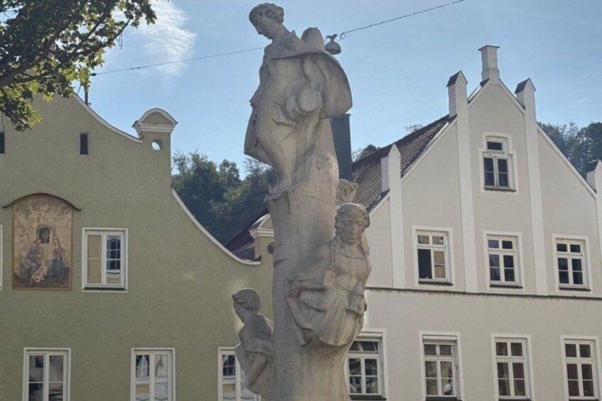 A building with a statue in front, a mural on the left, and a white facade with windows. 3