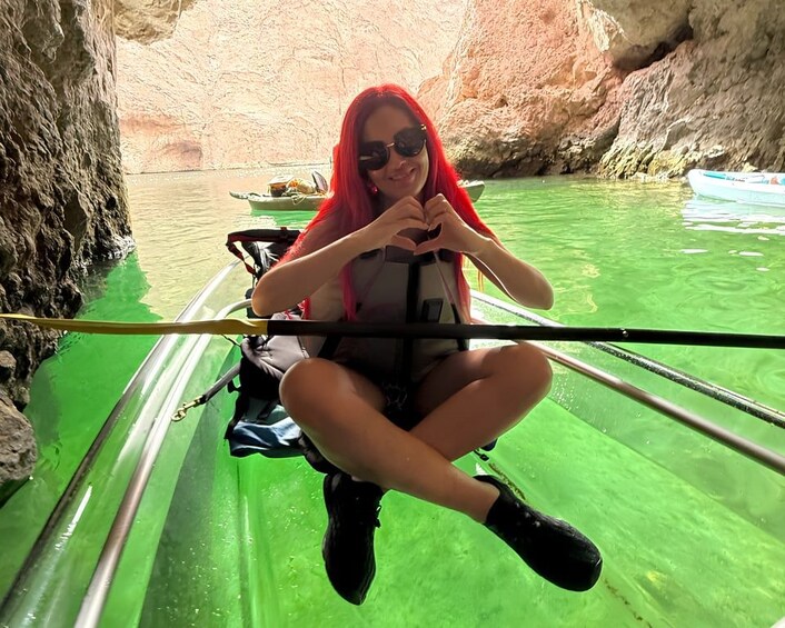 A person in a kayak on a green body of water, with rocky cliffs in the background. 1