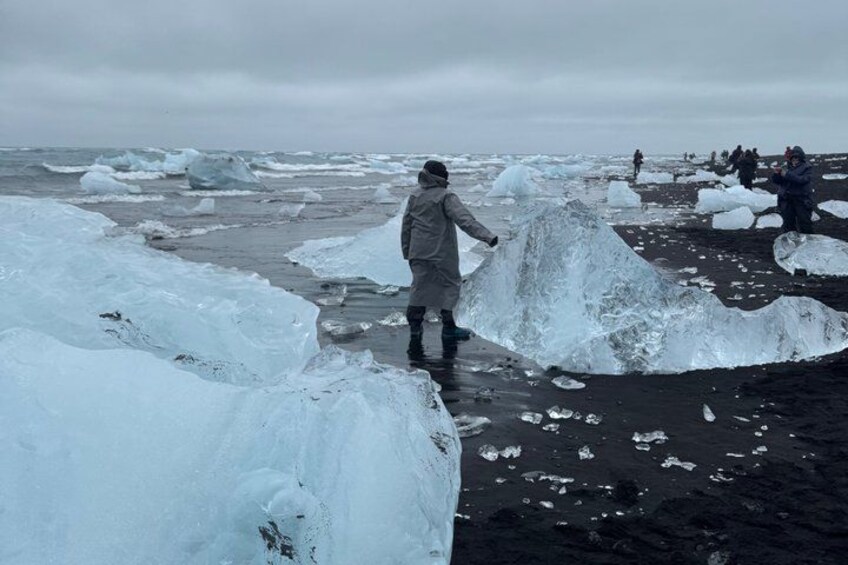A person walking on a beach with large ice formations. 1