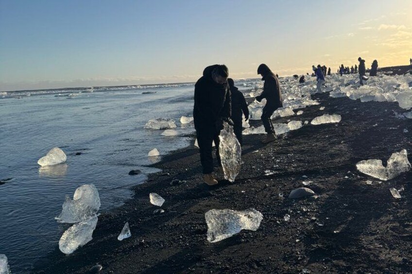 A beach with people walking among ice chunks. 3
