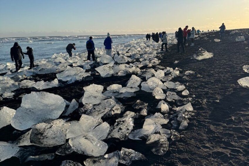 People standing on a beach with large ice chunks scattered around. 5
