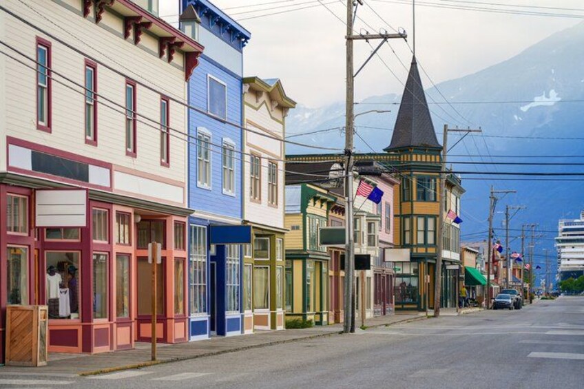 A colorful street with buildings, a church steeple, and a mountain in the background. 4