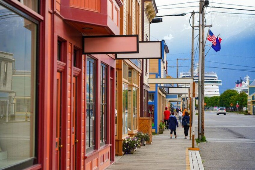 A coastal town with red buildings, a wooden boardwalk, and a cruise ship in the background. 2