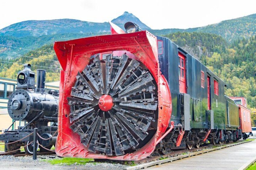 A steam locomotive with a large red wheel, a smaller black engine, and a red caboose. 1