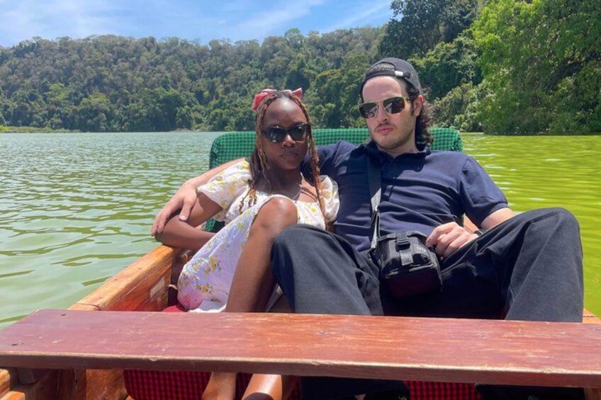 Two people in a boat on a lake surrounded by greenery. 2
