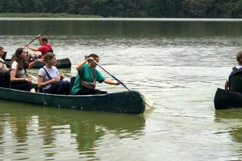 A group of people rowing a green boat on a calm lake. 5
