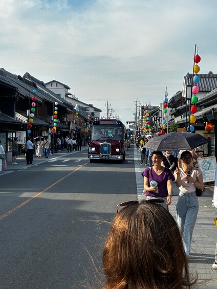 Une rue bordée de bâtiments traditionnels, un autobus et des passants. 3