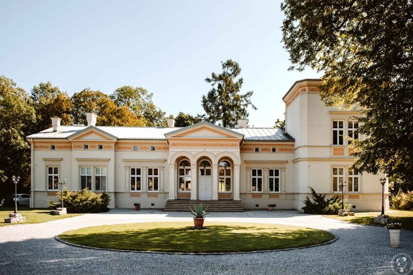 A large, classical-style building with a symmetrical facade, arched windows, and a central entrance with steps. 3