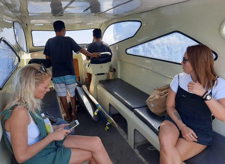 Ein kleines, geschlossenes Fahrzeuginnere mit zwei sitzenden Personen, von denen eine ein Smartphone hält, und zwei Personen, die im Fond stehen. 4