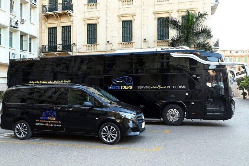 A black minivan and a black tour bus parked on a street. 2