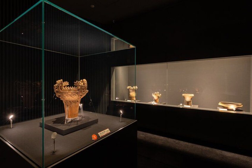 A glass display case with a golden crown and several smaller artifacts. 2