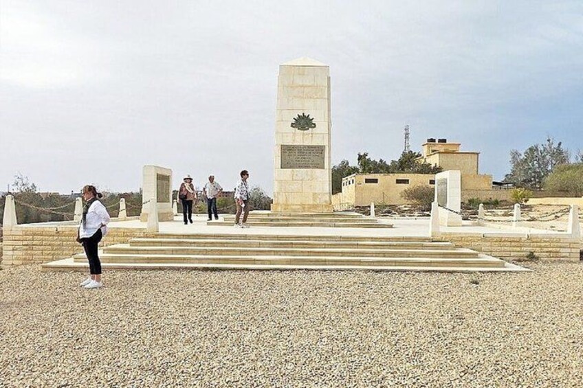 A memorial monument with inscriptions, surrounded by a gravel area with steps leading up to it. 1