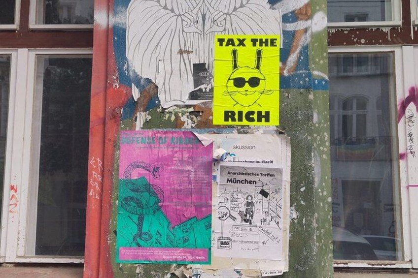 A bulletin board with various posters and flyers, including one that says 'TAX THE RICH'. 4