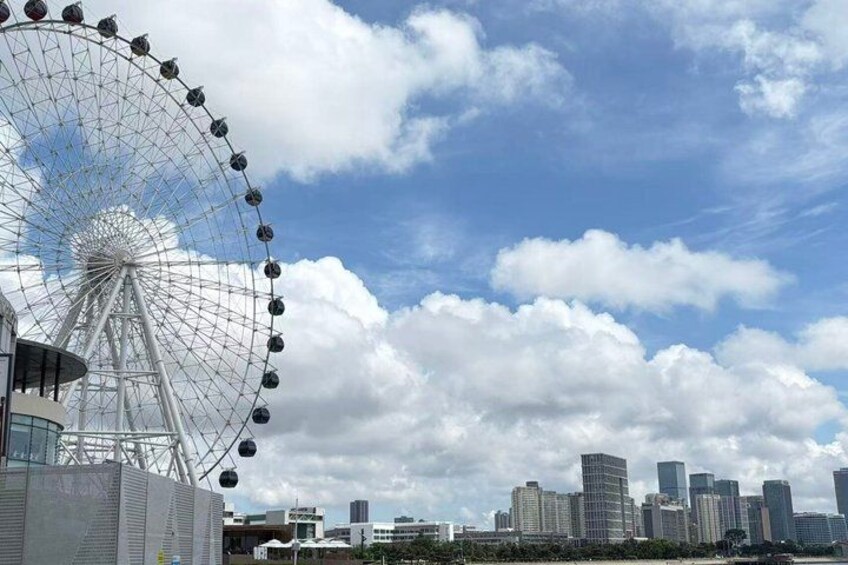 A Ferris wheel, a city skyline, and a partly cloudy sky. 1