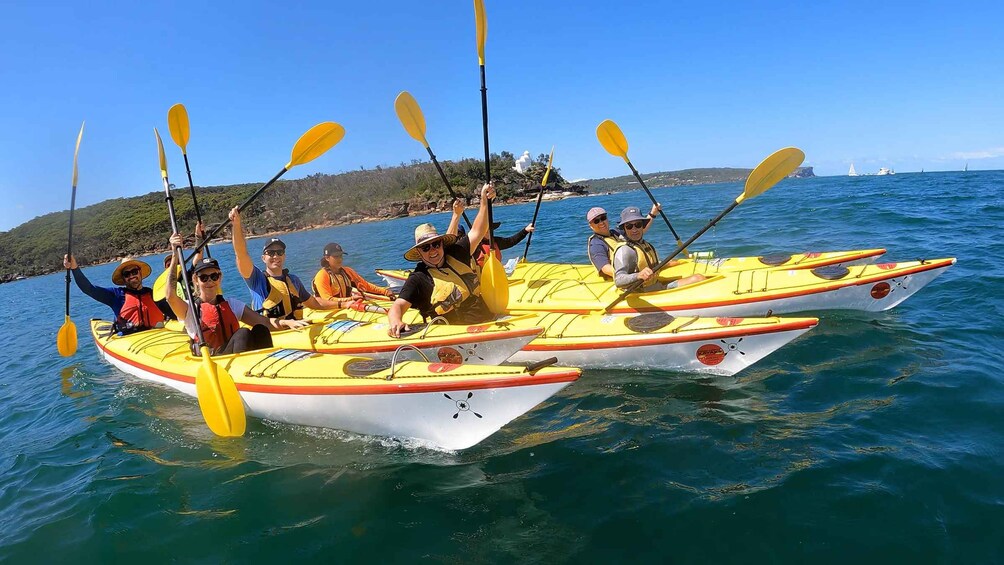 Un groupe de personnes pratiquant le kayak sur une mer calme, sous un ciel dégagé. 3