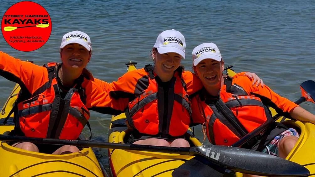 Trois personnes pratiquent le kayak dans le port de Sydney, portant des gilets de sauvetage et des casquettes. 5