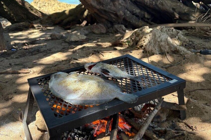 A fish grilling on a portable grill outdoors. 5