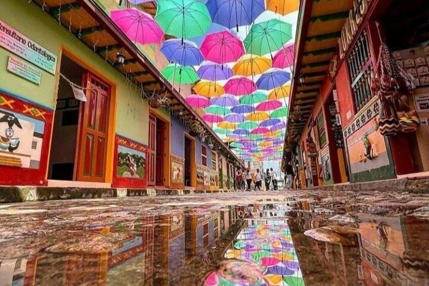 A street with colorful umbrellas hanging overhead and a reflective water surface. 3