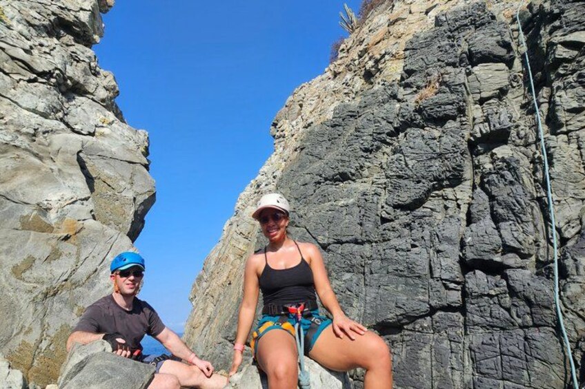 Two people sitting on rocks in a rocky canyon with a clear sky. 5