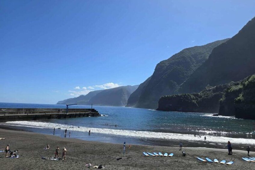 A beach with people, surfboards, and a pier extending into the water. 5