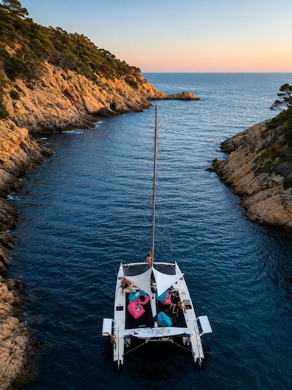 A sailboat anchored in a narrow waterway surrounded by rocky cliffs. 3