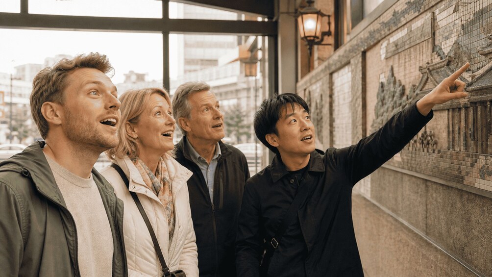 A group of people looking at a wall with historical engravings. 4