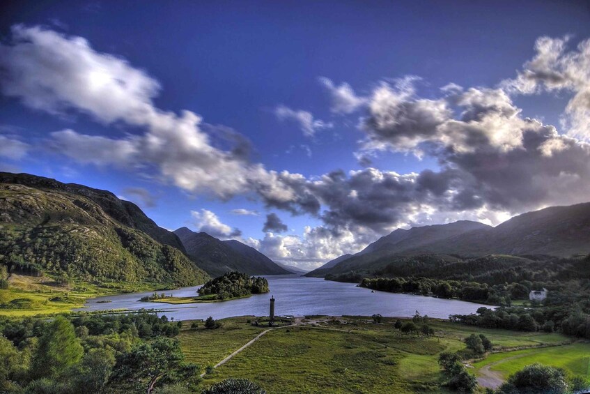 Un lac entouré de montagnes, une petite île et un ciel dégagé parsemé de nuages. 3