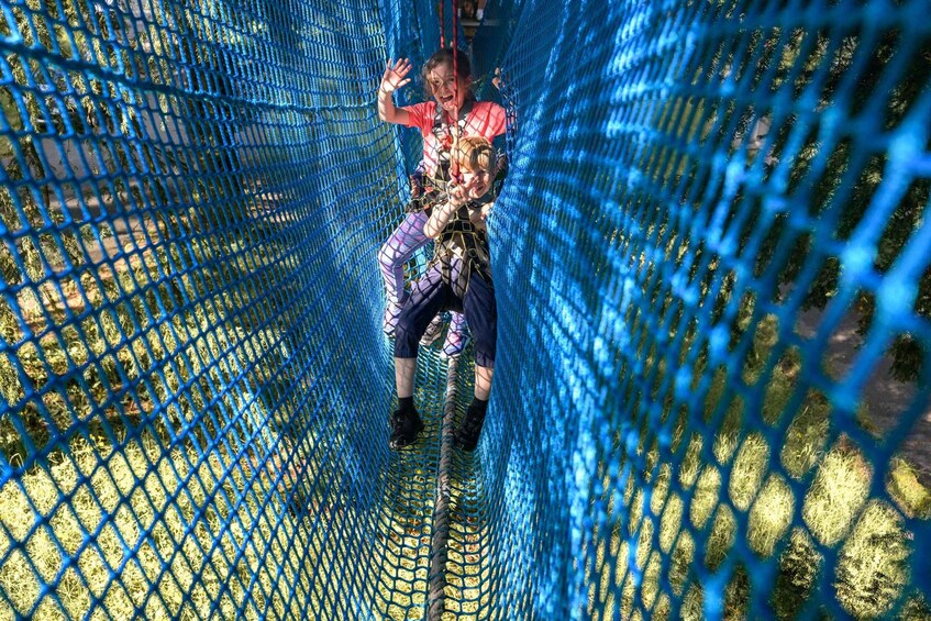 A person navigating a blue netted obstacle course. 5