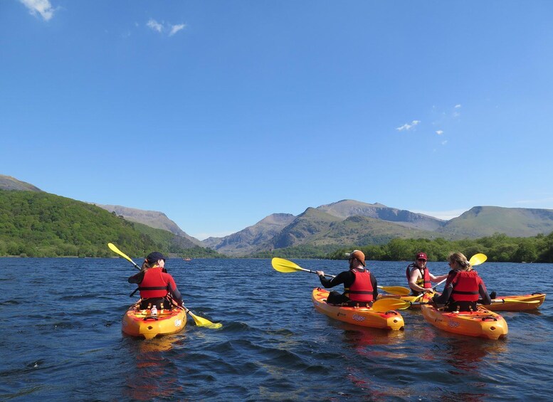 Four people kayaking on a lake with mountains in the background. 5