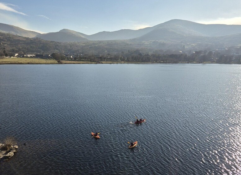 A calm lake with kayakers, surrounded by mountains and a clear sky. 3