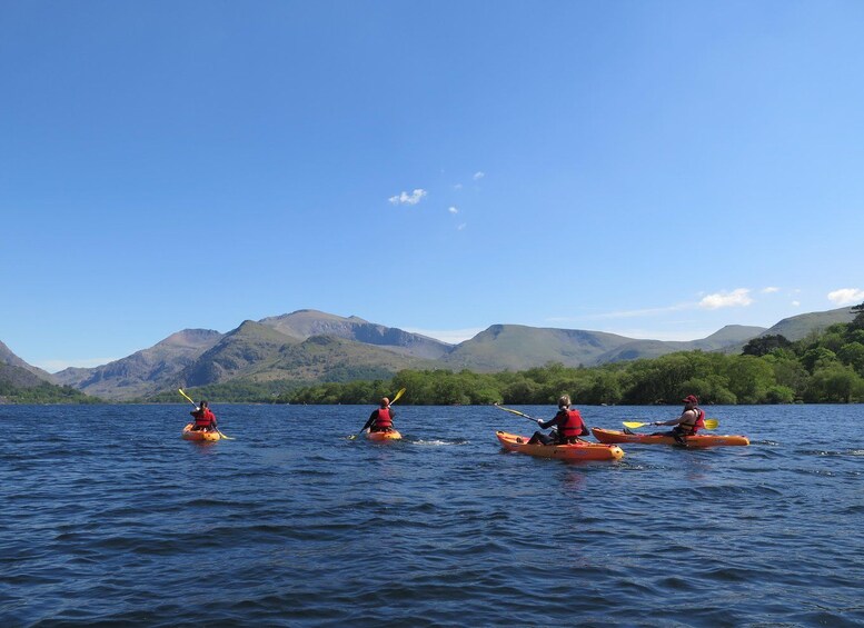 Three kayakers on a calm lake with mountains in the background. 4