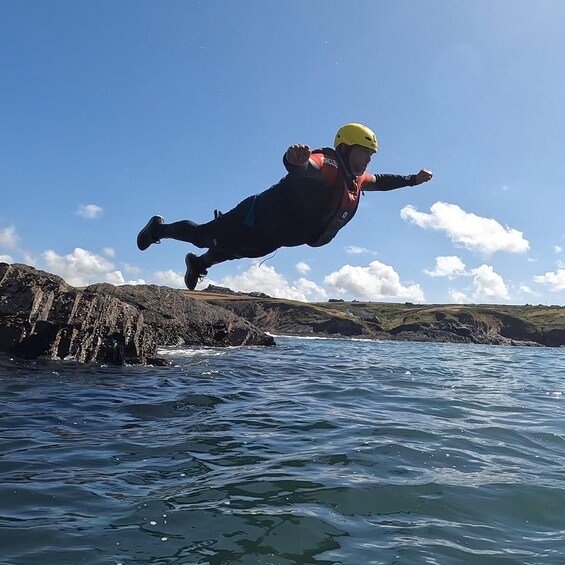 A person skydiving over a coastal landscape with rocky cliffs and waves. 5