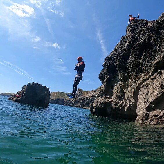 A person standing on a rocky cliff by the sea. 3