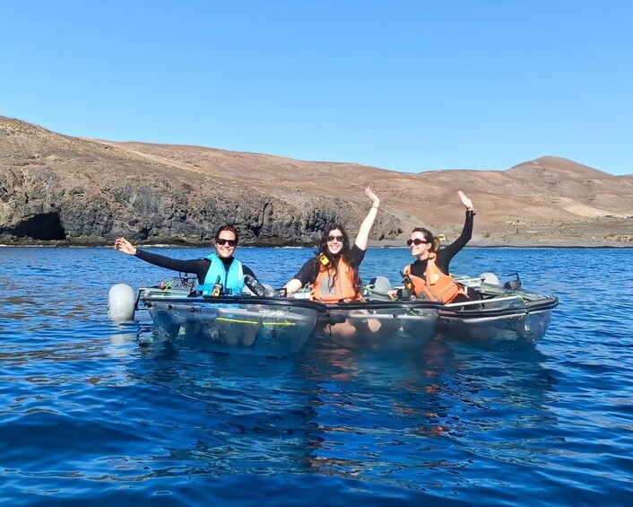 Three people in a small boat on a body of water with hills in the background. 1