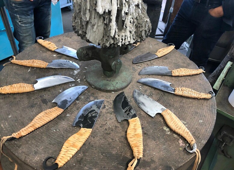 A circular wooden table with eight knives with woven handles arranged around it. 2