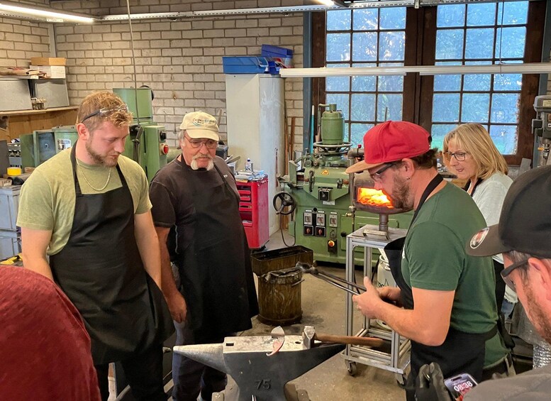 A workshop with people engaged in metalworking activities, including a forge and an anvil. 3