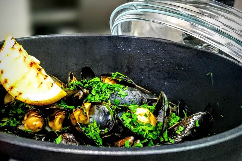 A bowl of mussels garnished with parsley and lemon. 1