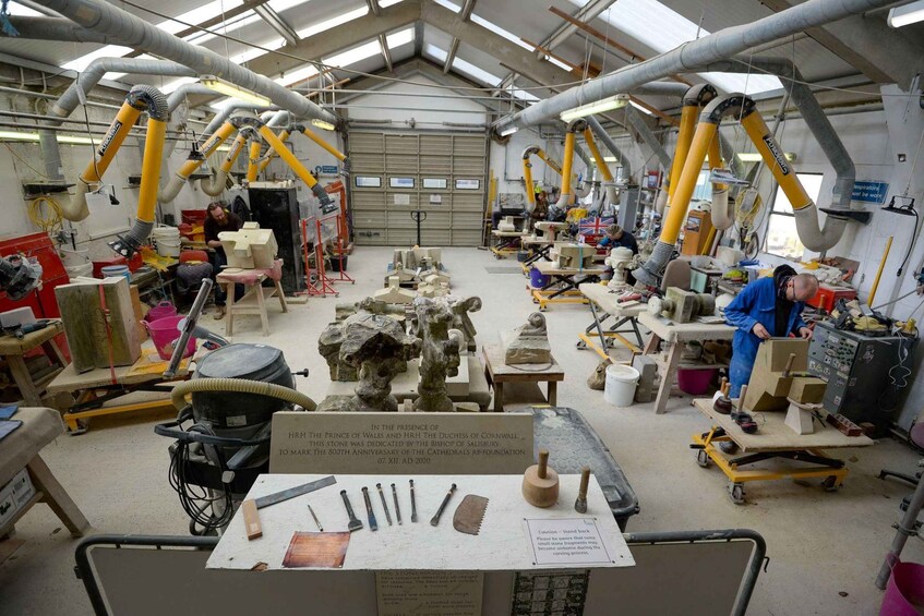 A stone carving workshop with multiple workstations, tools, and sculptures in progress. 3
