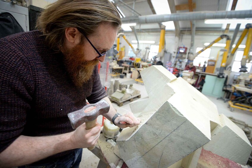 A person working with a hammer and chisel on a stone block. 2
