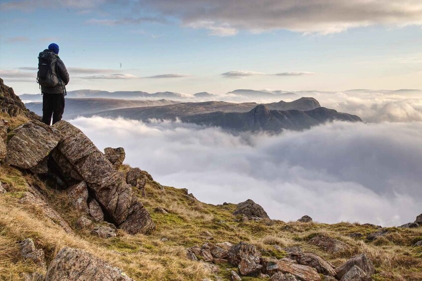 A hiker on a rocky mountain edge overlooking a valley of clouds. 3