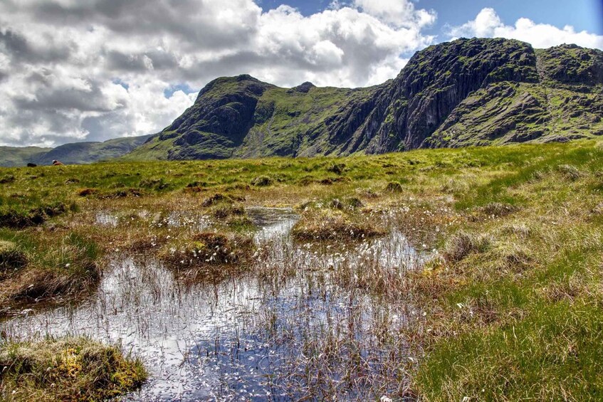 A mountainous landscape with a small body of water reflecting the sky. 4
