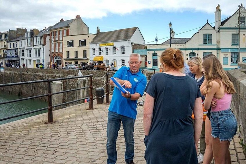 A group of people walking along a waterfront promenade with historic buildings in the background. 2