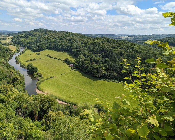 A river winding through a lush valley with dense forests and rolling hills. 4