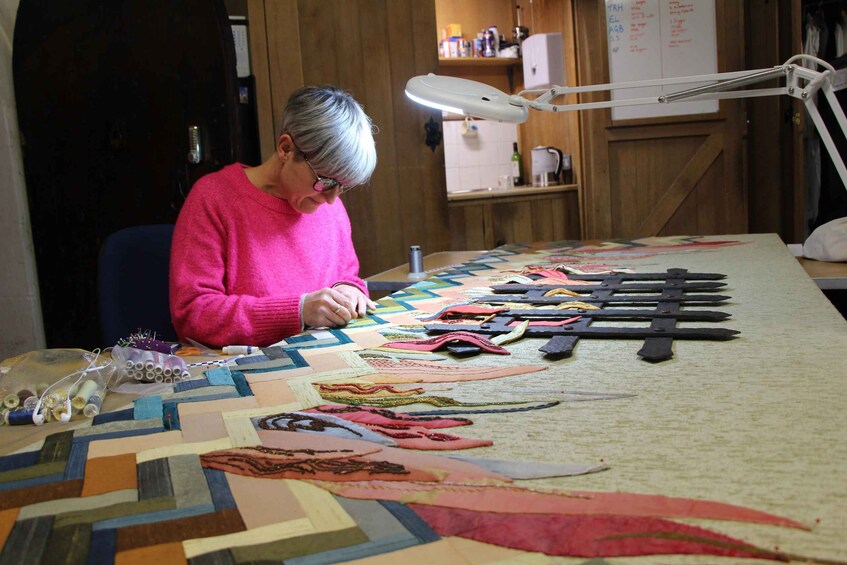A person sewing a colorful quilt with various patterns and designs. 4
