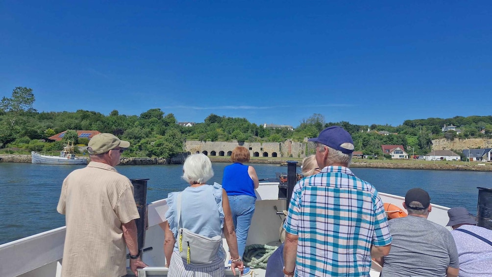 A group of people on a boat, a river, and a stone bridge in the background. 2